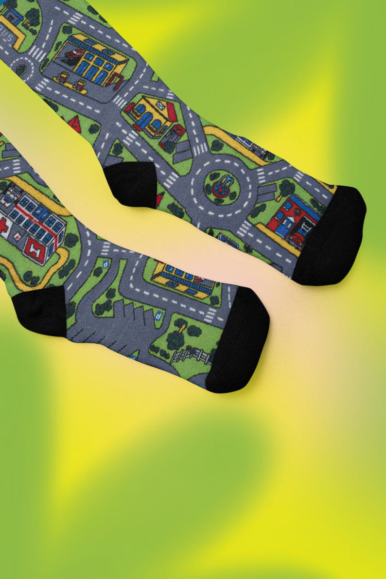 May include: A pair of black socks with a playful design featuring a miniature city with roads, buildings, and trees. The socks are made of a soft, comfortable material and are perfect for adding a touch of whimsy to any outfit.