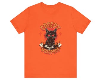 Puede incluir: Camiseta naranja con un diseño de Halloween. Presenta un gato negro con ojos rojos, una calabaza y dos fantasmas. El texto "Creepy Whispers" está encima del gato. El diseño tiene un tema vintage.