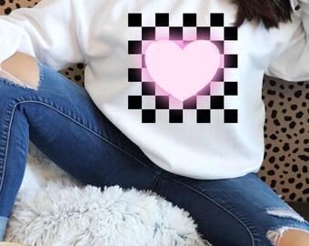 May include: White sweatshirt with a pink heart in a black and white chequered pattern.