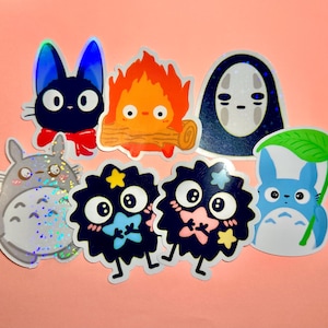 May include: A collection of colorful anime-style stickers featuring various characters. The stickers include a black cat with a red bow, a fiery creature, a faceless spirit, a gray Totoro, and several soot sprites.