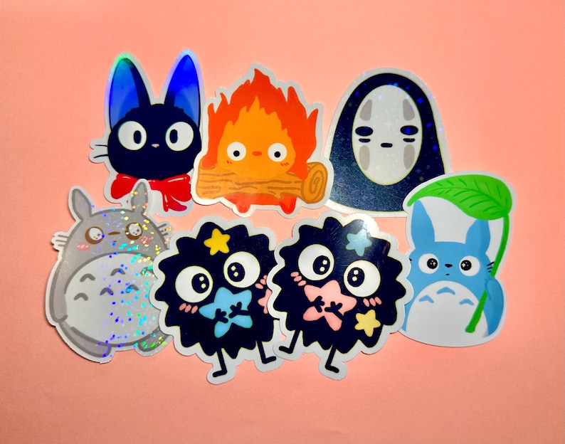 May include: A collection of colorful anime-style stickers featuring various characters. The stickers include a black cat with a red bow, a fiery creature, a faceless spirit, a gray Totoro, and several soot sprites.