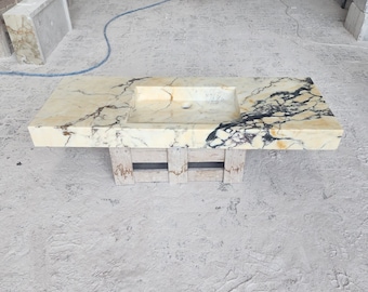 May include: A white marble bathroom vanity top with a rectangular sink and black veining. The vanity top is supported by a wooden frame.