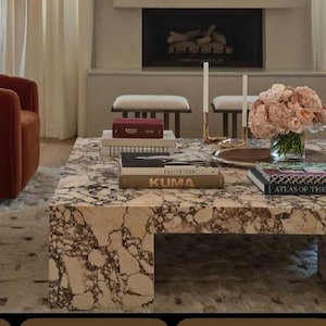 May include: A white ceramic mug with a black handle and the text "But First, Coffee" in a bold, black font. The mug is sitting on a wooden surface. The mug is approximately 4 inches tall.