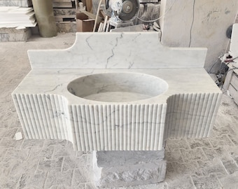 May include: A white marble bathroom sink with a rectangular backsplash and a fluted base. The sink is empty and ready for use.