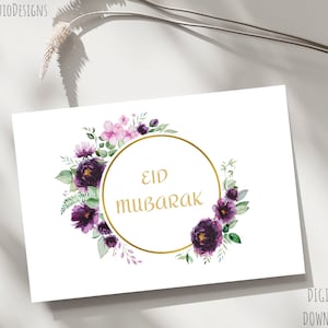 Pode incluir: Um cartão imprimível com um círculo dourado e o texto "Eid Mubarak" rodeado de flores de aquarela roxas e rosas.