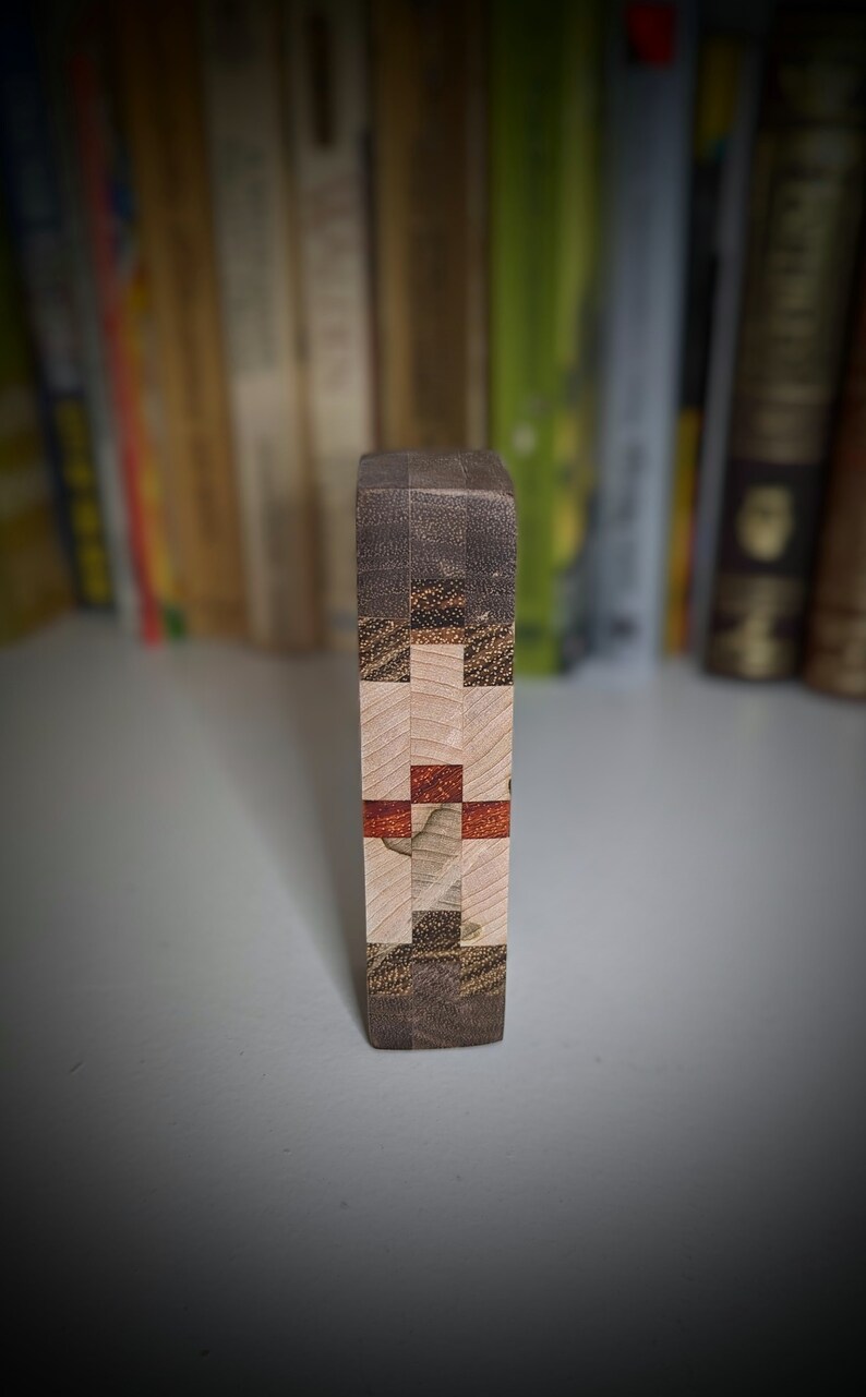 May include: A wooden block with a geometric pattern of different coloured woods. The block is made of light brown, dark brown, and red wood.