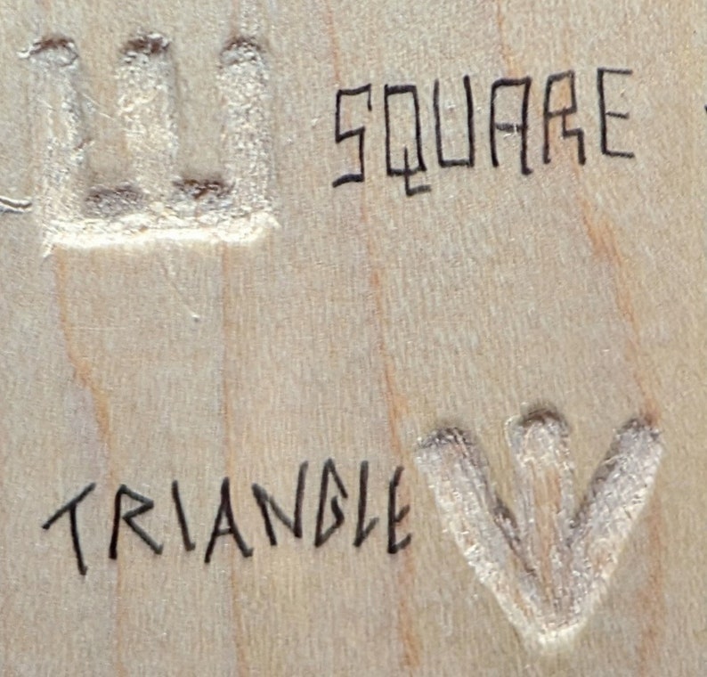 May include: A close-up of a wooden surface with the words "SQUARE" and "TRIANGLE" written in black ink. A square and a triangle are carved into the wood.