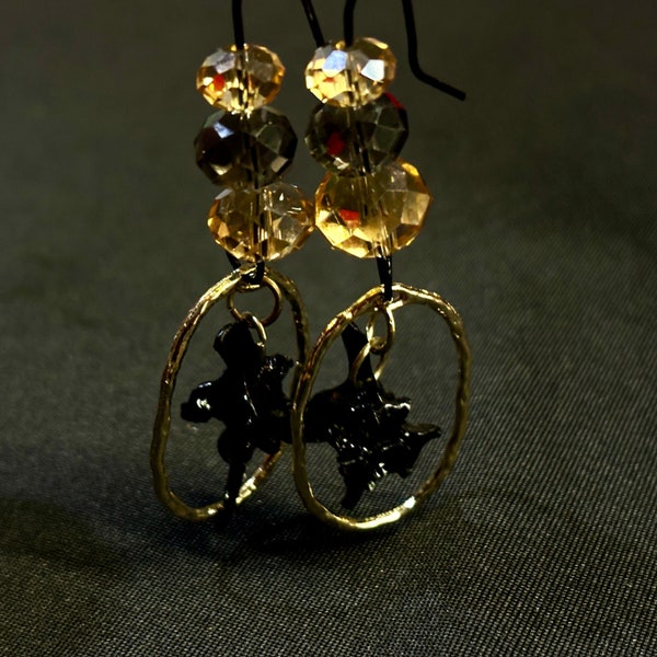 A shimmering  pair of black and gold irridesant bead drop earrings with hand painted black boa constrictor vertebrae.