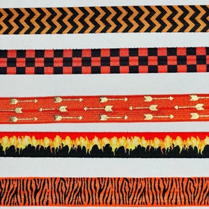 May include: Five different orange and black patterned elastic bands. The patterns include polka dots, zigzags, checkered, arrows, and flames.