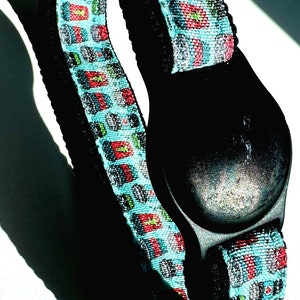 May include: A black and blue patterned wristband with a black button.