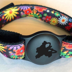 May include: A black and colorful floral patterned wristband with a black round tracker attached.