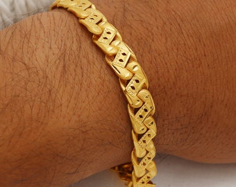 May include: A gold bracelet with a detailed, patterned design. The bracelet is made of thick, linked chains.
