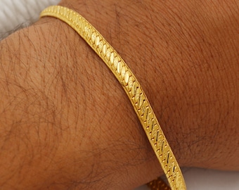 May include: A gold bracelet with a textured, snake-like chain design.