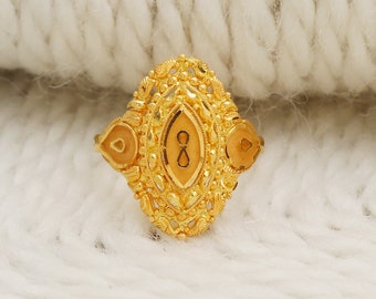 May include: A gold ring with an intricate design featuring a central oval-shaped stone with an infinity symbol. The ring has two smaller stones on either side of the central stone.