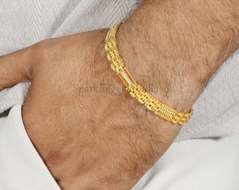 May include: A gold bracelet featuring a multi-link chain design with a repeating rectangular pattern. The bracelet has a polished finish and a secure clasp mechanism, displaying a consistent metallic yellow tone throughout the entire piece.