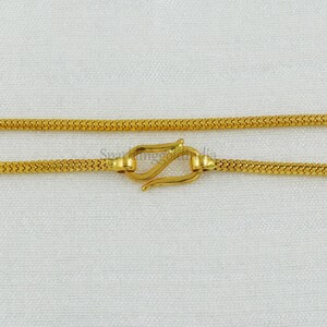 Puede incluir: Un collar de cadena de oro con cierre de mosquetón. La cadena está hecha de un tejido fino y delicado.