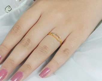 May include: A gold ring featuring a rectangular-shaped centerpiece adorned with small, clear, sparkling stones. The band is thin and polished, showcasing a minimalist design that sits comfortably on the finger, highlighting the metallic luster.