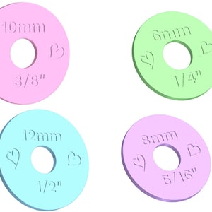 May include: Four colourful plastic rings with different sized holes. The rings are labelled with measurements in millimetres and inches. The rings are 10mm (3/8"), 6mm (1/4"), 12mm (1/2"), and 8mm (5/16").