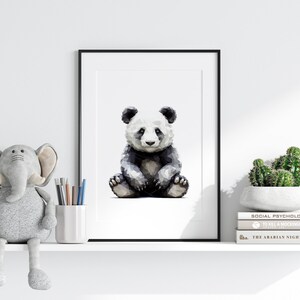May include: A black and white geometric panda bear illustration in a framed print on a white shelf with a gray elephant plush toy and a potted cactus.