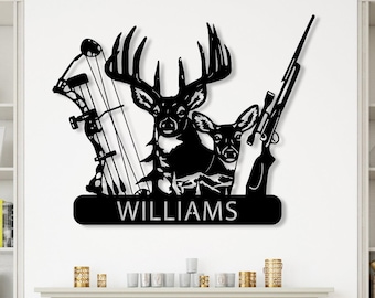 May include: Black metal wall art featuring a deer, rifle, and bow and arrow design. The word "WILLIAMS" is displayed on a banner below the deer. The artwork is mounted on a white wall above a fireplace.