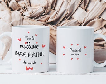 Puede incluir: Dos tazas de cerámica blanca con texto negro y rojo. Una taza dice "Tu es la meilleure marraine du monde" con acentos de corazón rojo. La otra taza dice "Prenom(s) ou texte" con acentos de corazón rojo.