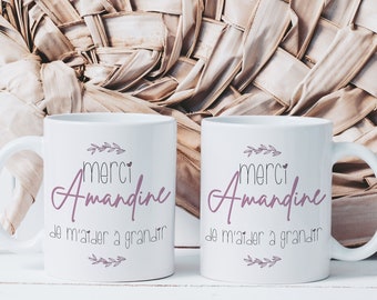 May include: Two white ceramic mugs with black text that reads "Merci Amandine de m'aider a grandir" with a small pink heart and a floral design.