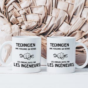 Puede incluir: Dos tazas de cerámica blanca con texto negro y un gráfico de llave inglesa. El texto dice "Technicien, une personne qui repare les erreurs faites par les ingenieurs".