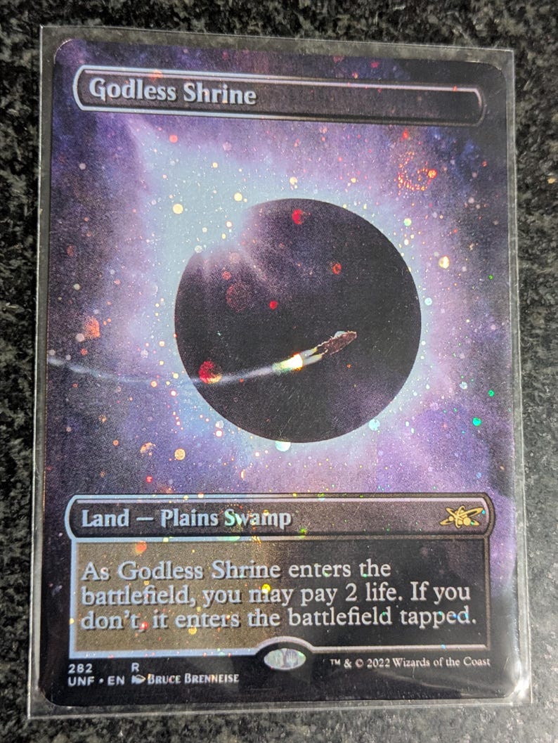 May include: A "Godless Shrine" trading card with a cosmic background, a dark planet, and a spaceship. The card is a "Land - Plains Swamp" card. Text on the card includes the card's name, type, and rules text.