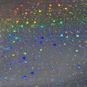 May include: A close-up of a shimmering, iridescent surface with a multitude of colorful, circular specks. The specks range in size and color, including red, orange, yellow, green, blue, and purple, creating a vibrant, speckled effect.
