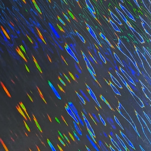 May include: Abstract holographic pattern with a dark background. The design features diagonal streaks of color, including blue, green, yellow, and orange, creating a shimmering, iridescent effect. The overall aesthetic is modern and visually dynamic.