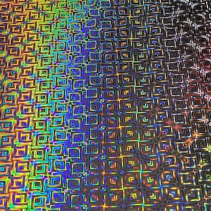 Könnte beinhalten: Nahaufnahme einer holografischen Folie mit einem sich wiederholenden quadratischen Muster. Die Oberfläche reflektiert ein Farbspektrum, einschließlich Gelb, Grün, Blau und Lila. Das Muster erzeugt einen schimmernden, irisierenden Effekt, geeignet für Bastel- oder Dekorationszwecke.