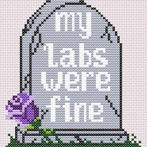 以下が含まれることがあります： 「My labs were fine」という文字と紫色のバラが描かれたクロスステッチ刺繍の墓石です。