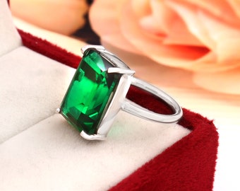 May include: A silver ring with a large, emerald green, rectangular gemstone.
