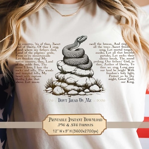 May include: Cream-coloured t-shirt featuring a coiled snake atop a rock formation, with the text "Don't Tread On Me" and a patriotic poem. The printable design is 30.48 cm W x 22.86 cm H.
