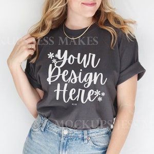 May include: A dark gray t-shirt with the text "Your Design Here" in white lettering. The shirt is being worn by a person with long blonde hair.
