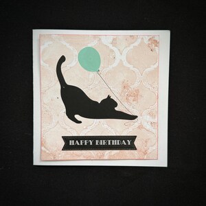 Stretching Black Cat Holding A Balloon On A Patterned Background Birthday Card With Options.