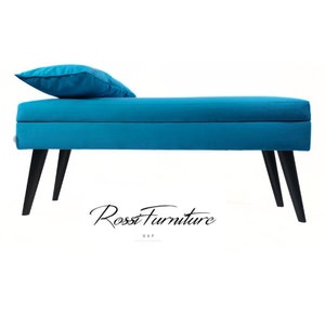 May include: A turquoise bench with black legs and a matching pillow. The bench has a rectangular shape and is made of a soft, upholstered material. The legs are angled and provide a modern touch. The bench is a piece of furniture.
