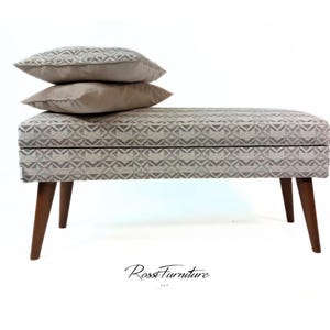 May include: A rectangular upholstered bench with a geometric pattern in shades of gray and white. Two matching pillows rest on top. The bench has four wooden legs. The image includes the text "Ross Furniture".