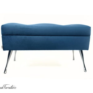Può includere: Una panca portaoggetti in velluto blu con gambe argentate. La panca ha una parte superiore curva e un design trapuntato.