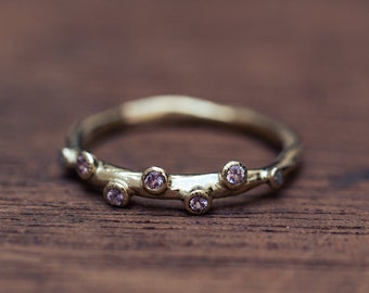 14K solid gold bubble engagement ring with raw texture set with 7 small pink sapphires in a bezel setting
