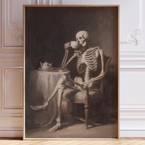 May include: A framed print showing a skeleton enjoying a cup of tea at a table. The artwork uses muted colours, with the skeleton and table setting as the main focus. The print is displayed against a white wall with decorative moulding.