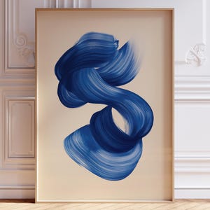 May include: A framed art print with an abstract design. It features a flowing swirl of deep blue brushstrokes on a neutral background. The artwork is displayed in a room with white paneling and a wooden floor, creating a modern aesthetic.