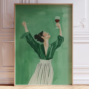 May include: A framed art print depicts a person in a green robe and striped skirt, raising a glass of red wine. The background is a solid green, and the frame is a light wood color. The artwork is displayed in a room with white paneling and a wooden floor.