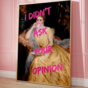May include: A painting of a woman in a yellow dress blowing a bubble with the words "I didn't ask your opinion" written in pink on the canvas.