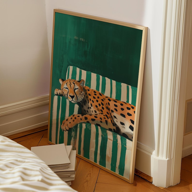 May include: A framed art print featuring a cheetah resting on a striped green and white chair. The cheetah has orange fur with black spots. The background is a solid green color.