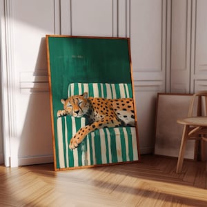 May include: A framed art print depicts a cheetah resting on a striped chair. The cheetah has a tan coat with black spots. The chair has green and white stripes. The background is a solid green color.