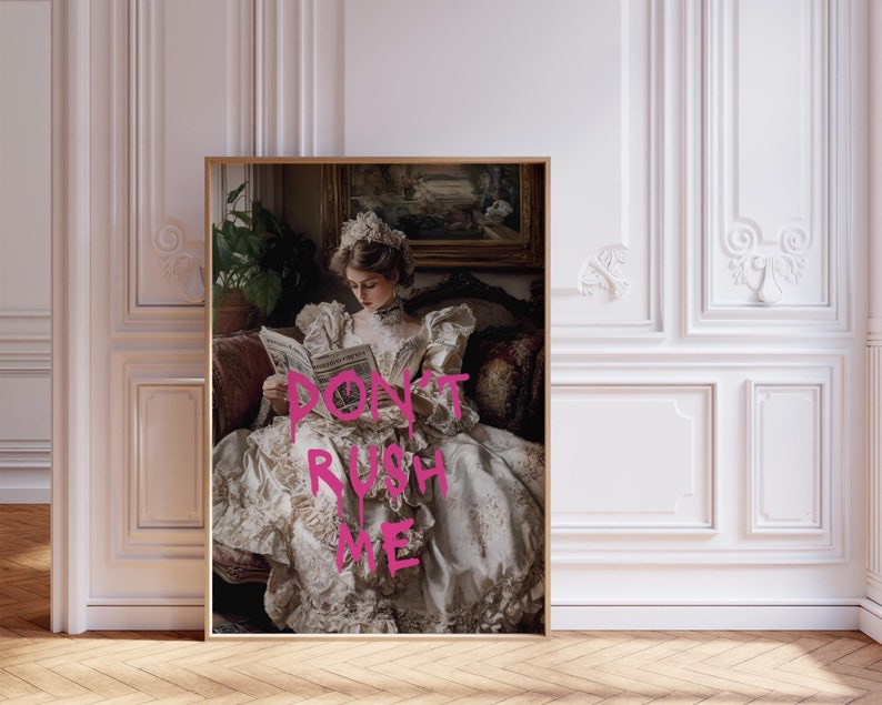 May include: A woman in a white dress with a floral pattern sits on a couch and reads a book. The text "Don't Rush Me" is written in pink spray paint on the book.