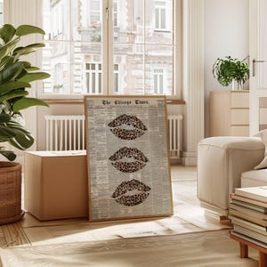 May include: A framed print displaying three leopard print lips against a backdrop of a vintage newspaper. The newspaper is titled "The Chicago Times." The print is in a room with neutral tones and natural light.