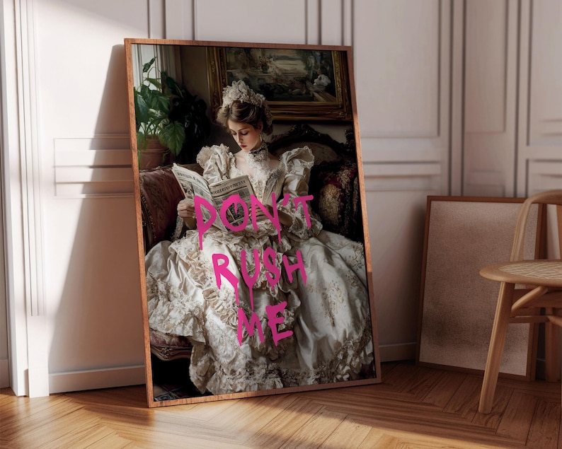May include: A woman in a white dress with gold embroidery sits on a couch and reads a newspaper. The words "Don't Rush Me" are written in pink spray paint across the dress.