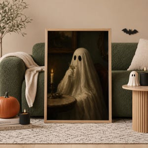 May include: A framed wall art print featuring a ghost draped in a white sheet, sitting at a round table with a lit candle and holding a martini glass. The scene is dark and moody, depicting the figure in a dimly lit room with vintage decor.